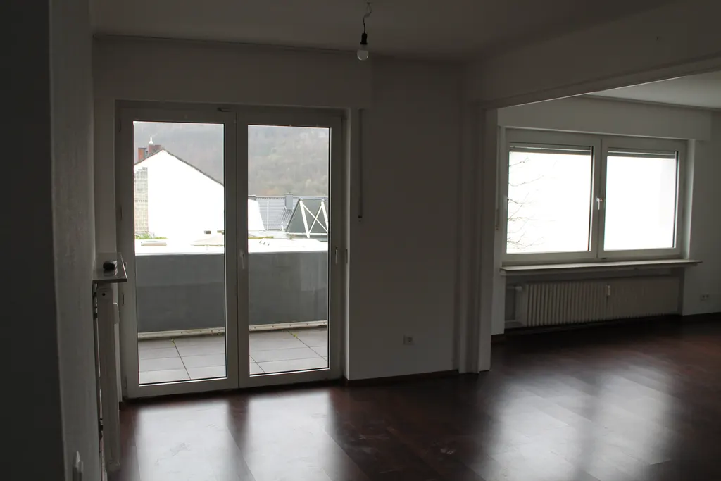 Großes Wohn- und Esszimmer mit Balkontür und dunklem Dielenboden