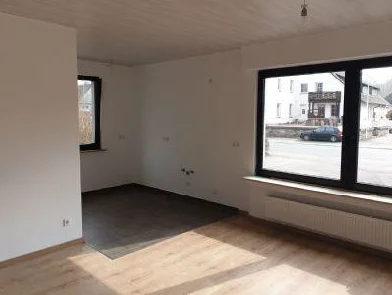 Heller Wohnbereich mit großem Fenster und Blick in den Küchenbereich